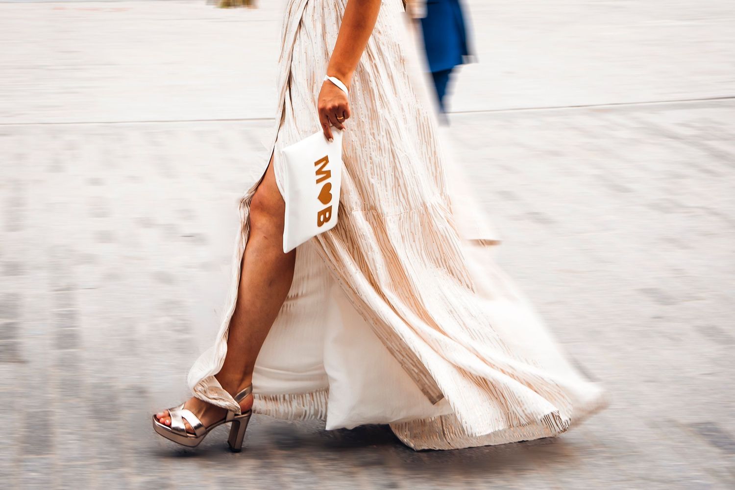 Close up of flowing white wedding dress and platform sandals while walking.