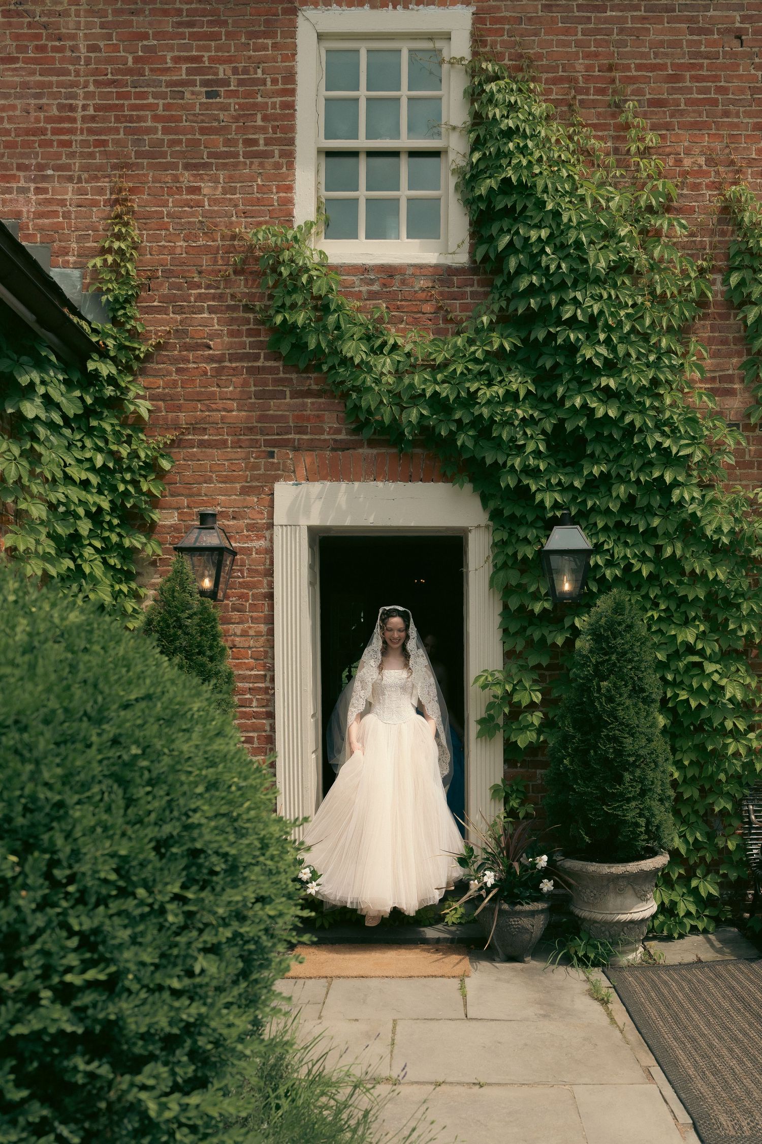 A romantic wedding portrait of a couple on a grassy hill against a backdrop of trees at dusk.