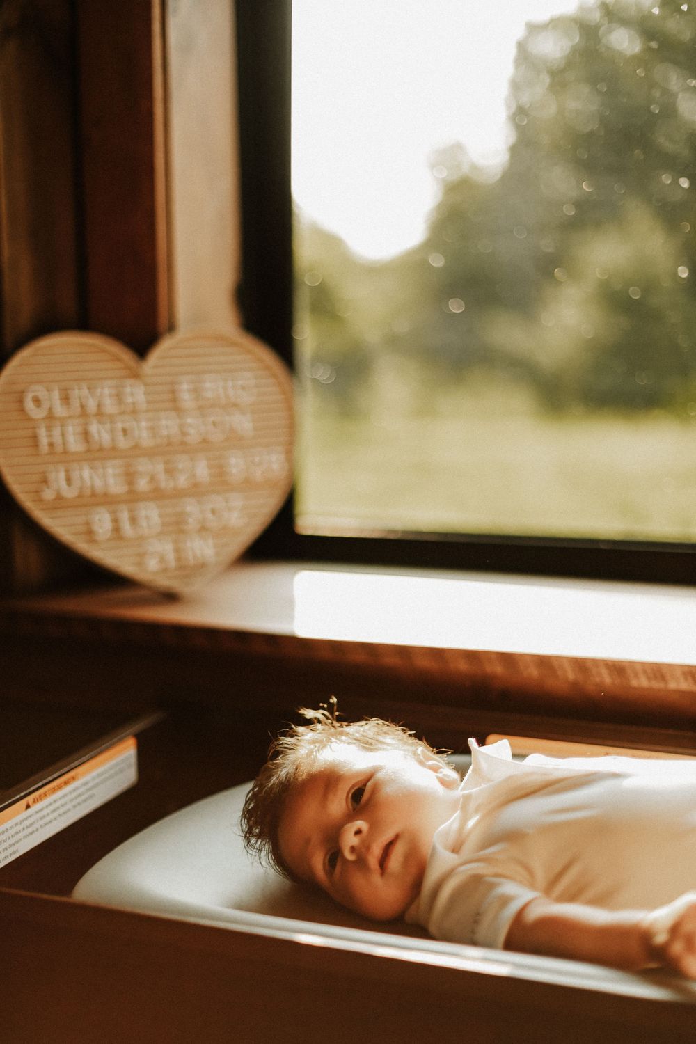 Sunlit nursery scene with heart-shaped name sign on windowsill.