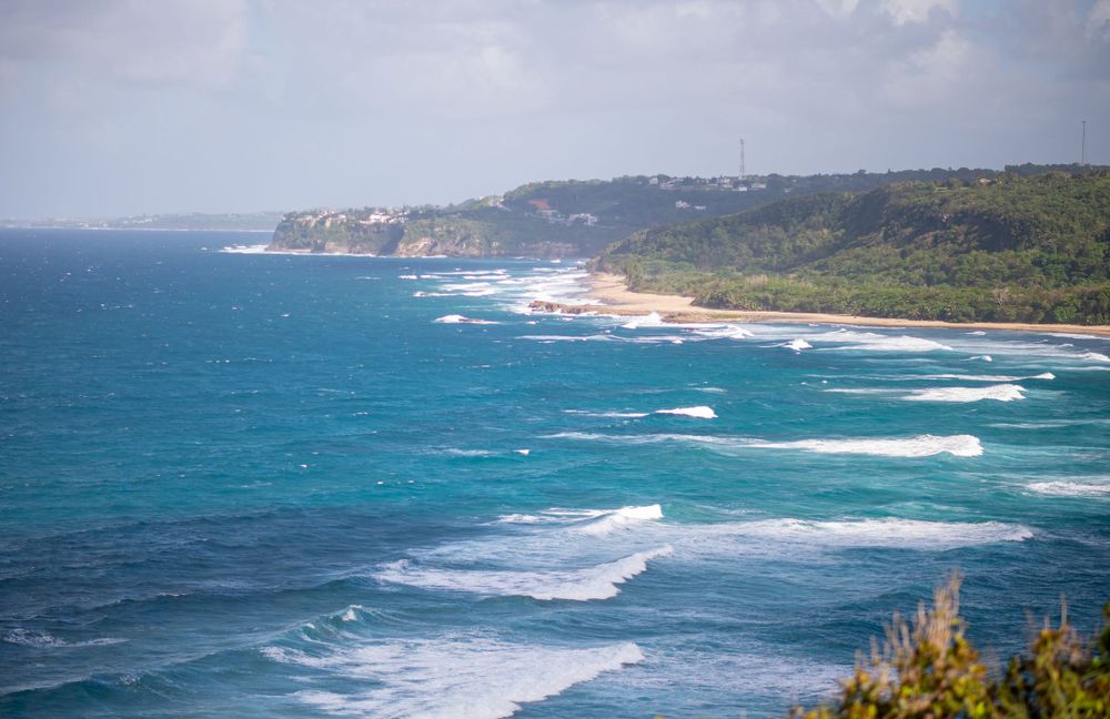 Dramatic coastline view with crashing waves and turquoise ocean waters against rocky cliffs.