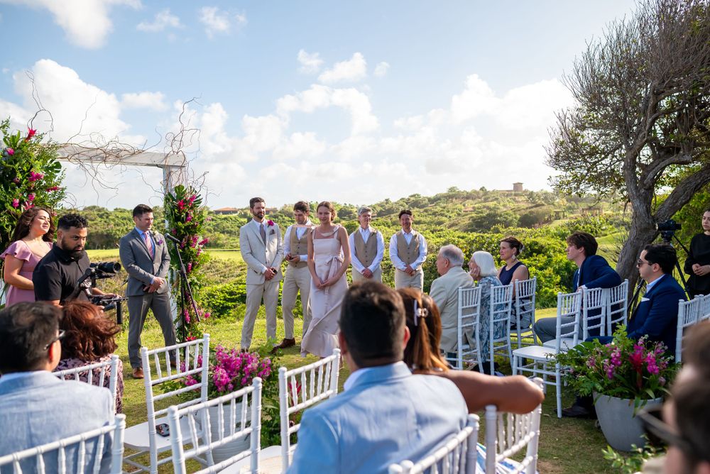 Wedding guests gathered for outdoor ceremony with white chairs and natural coastal backdrop.
