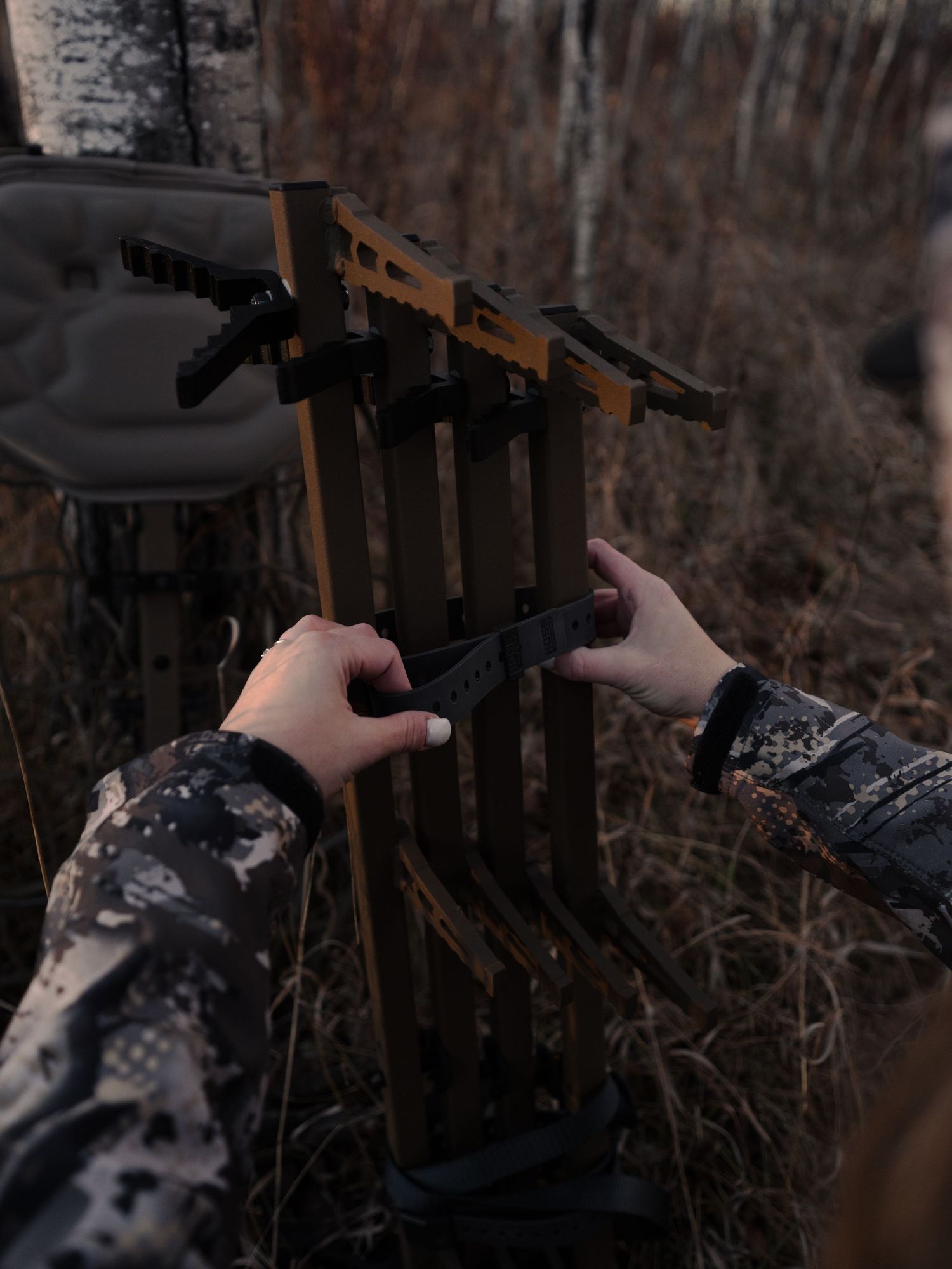 Close-up shot of hands adjusting tactical gear against dark forest background.