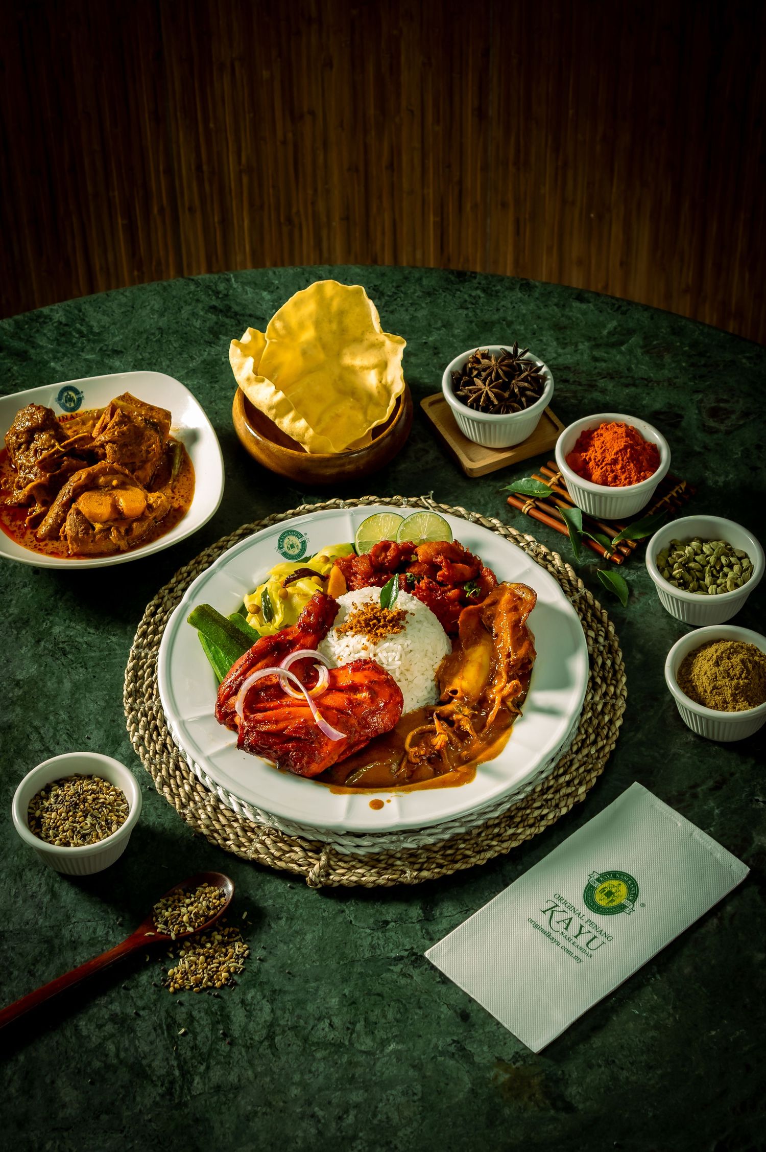 Elegantly plated spicy dishes with garnishes on dark green tablecloth with condiments.