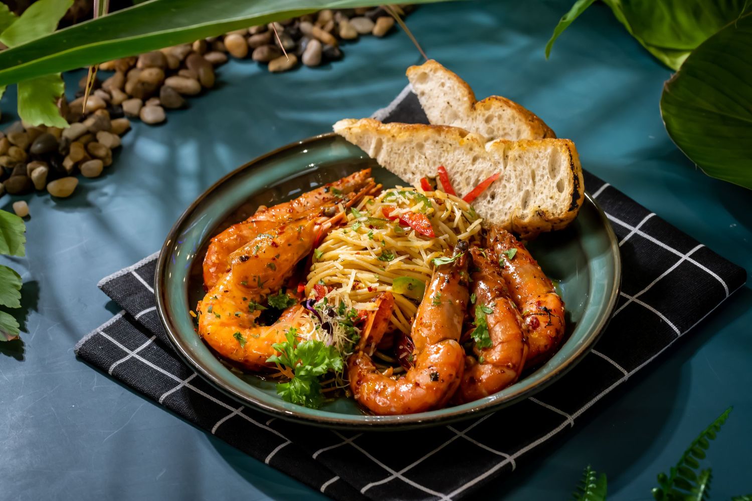 Grilled seafood and fish dishes arranged on dark plates with garnishes.