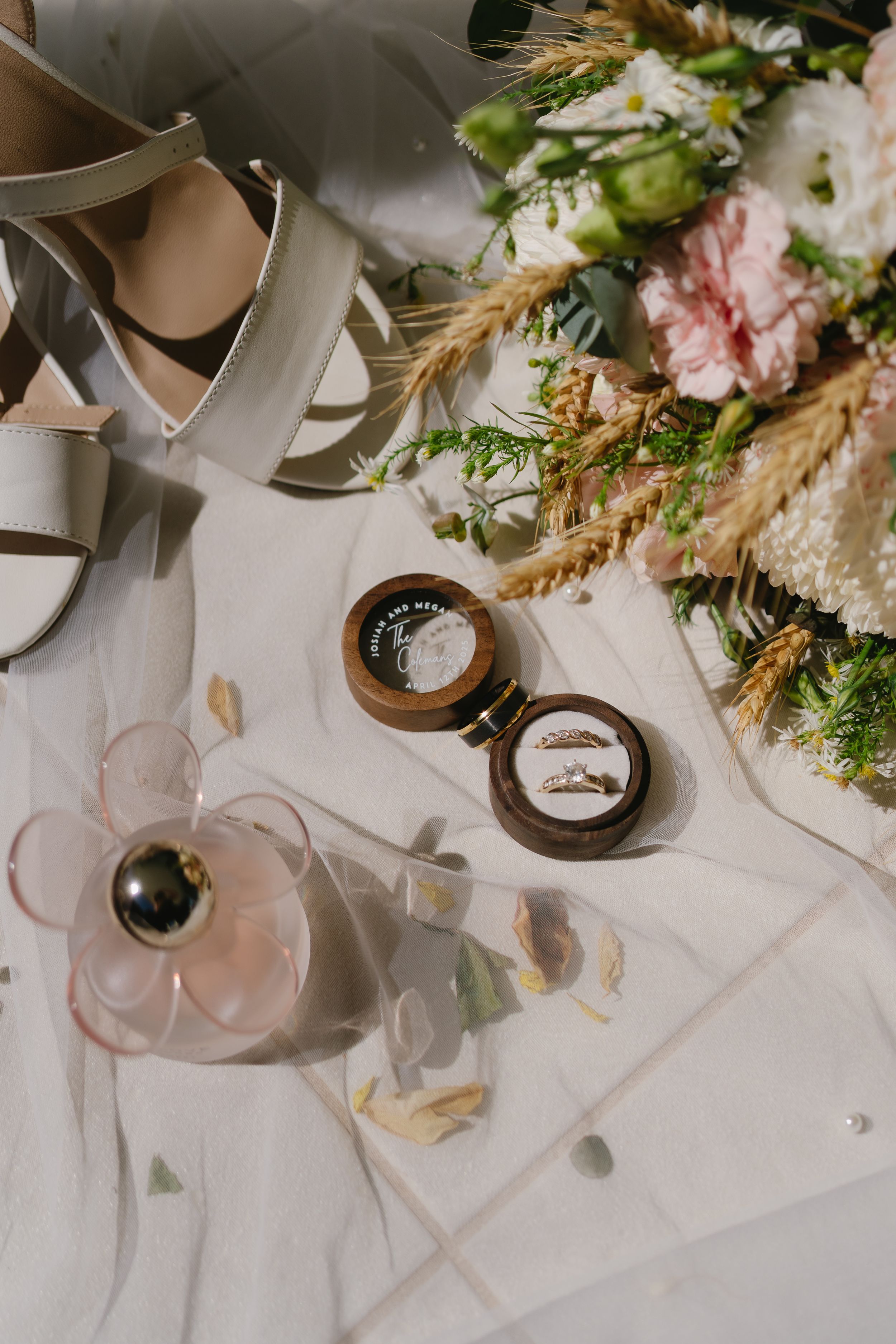 Wedding table details with delicate floral arrangements, wheat stalks, and glassware.