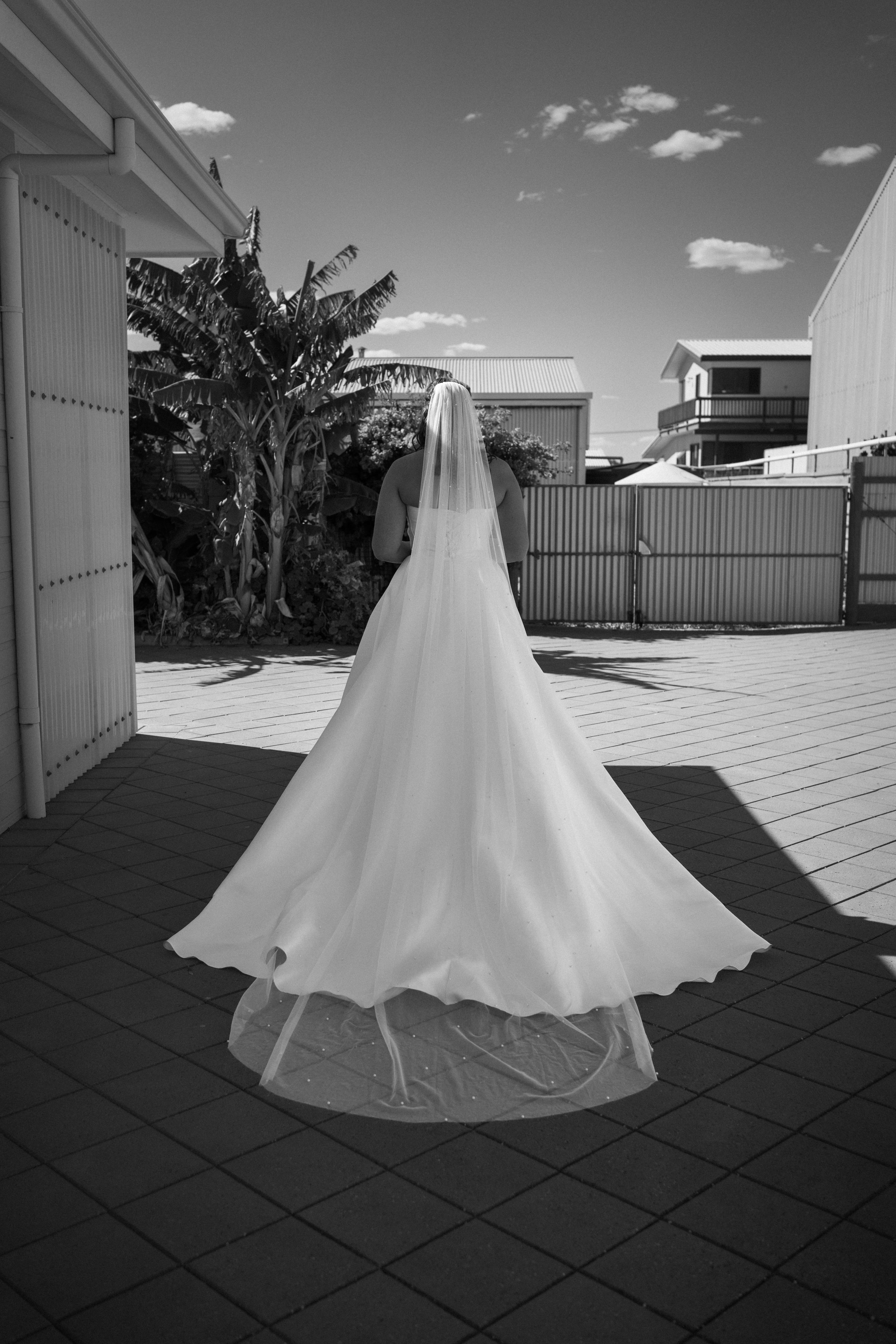Black and white photo of a wedding dress flowing in the breeze on an outdoor deck.