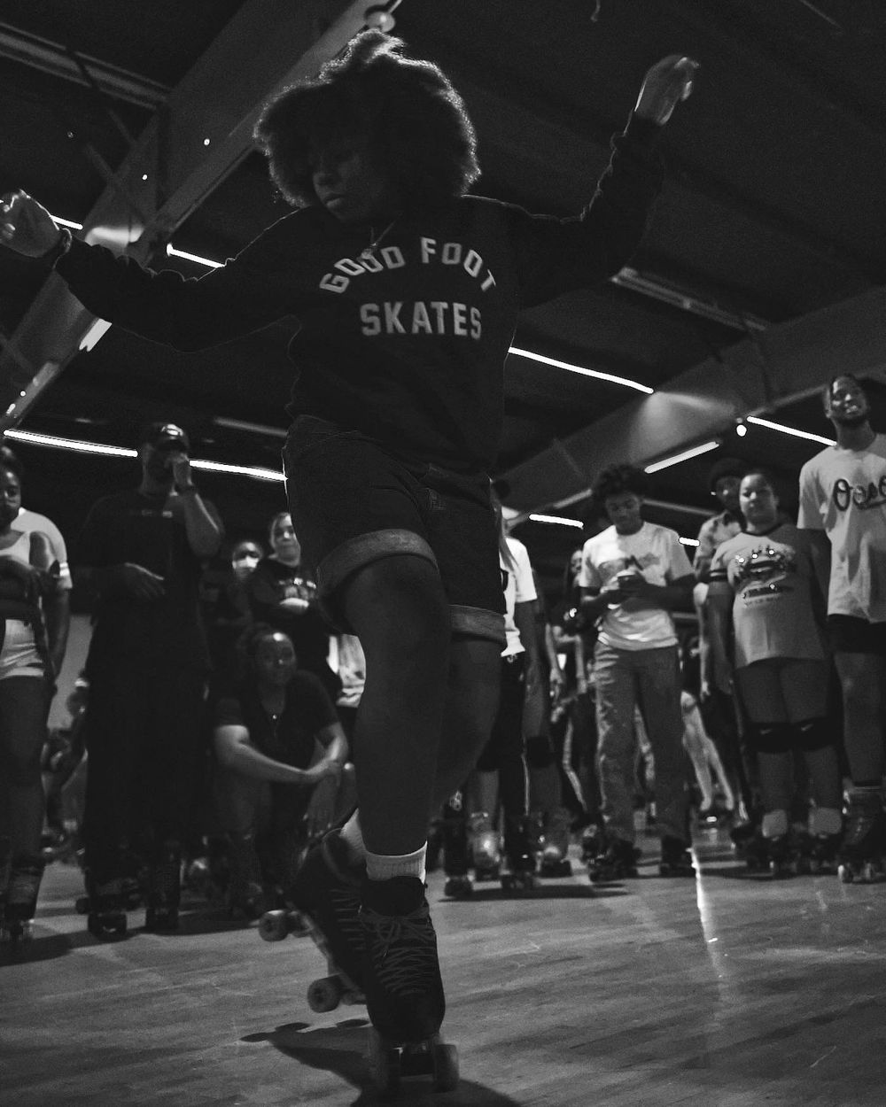 Person with good foot skates shirt jumping during energetic dance session in dark room.