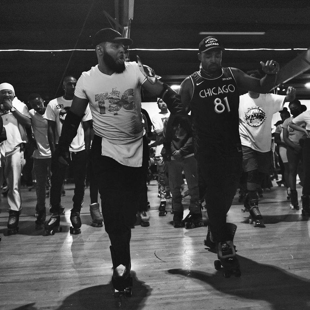 People dancing and moving together during indoor roller skating event in black and white.