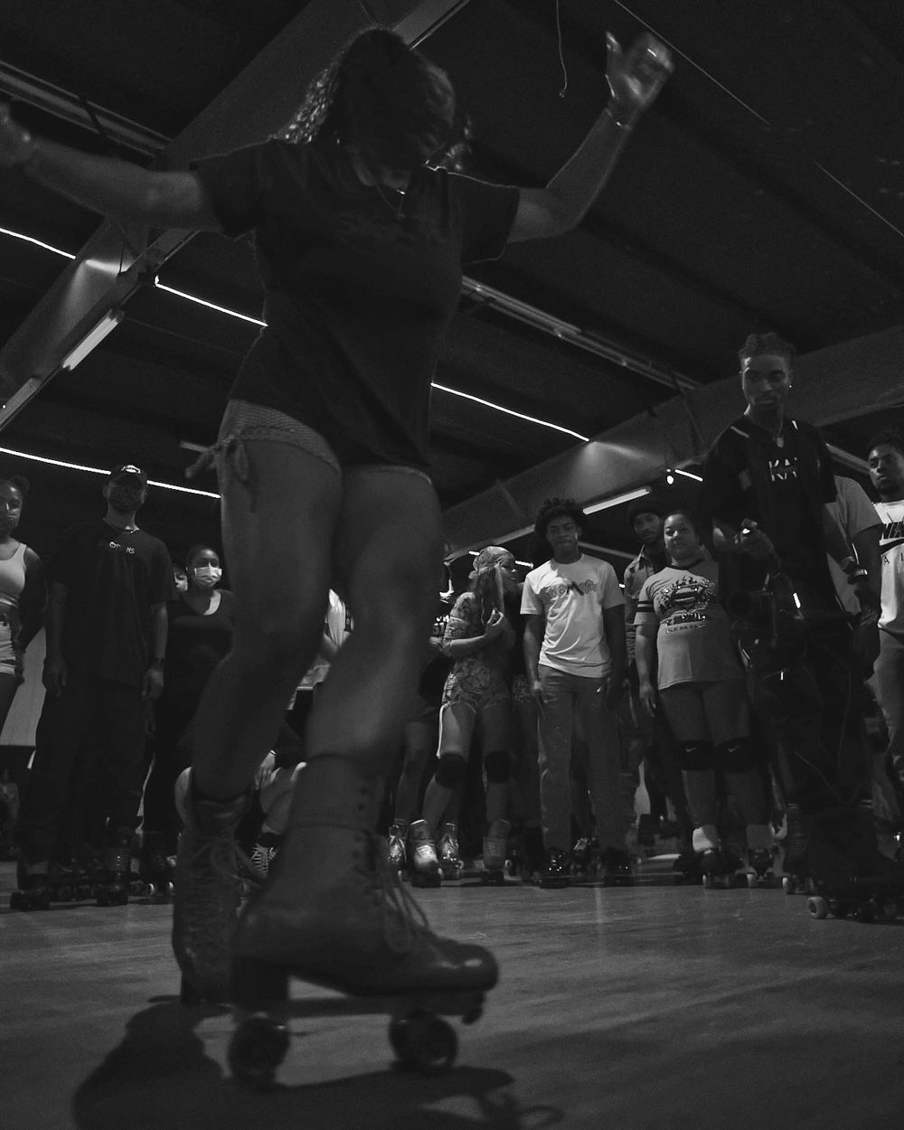 Roller skater performing moves on wooden floor during indoor skating event.