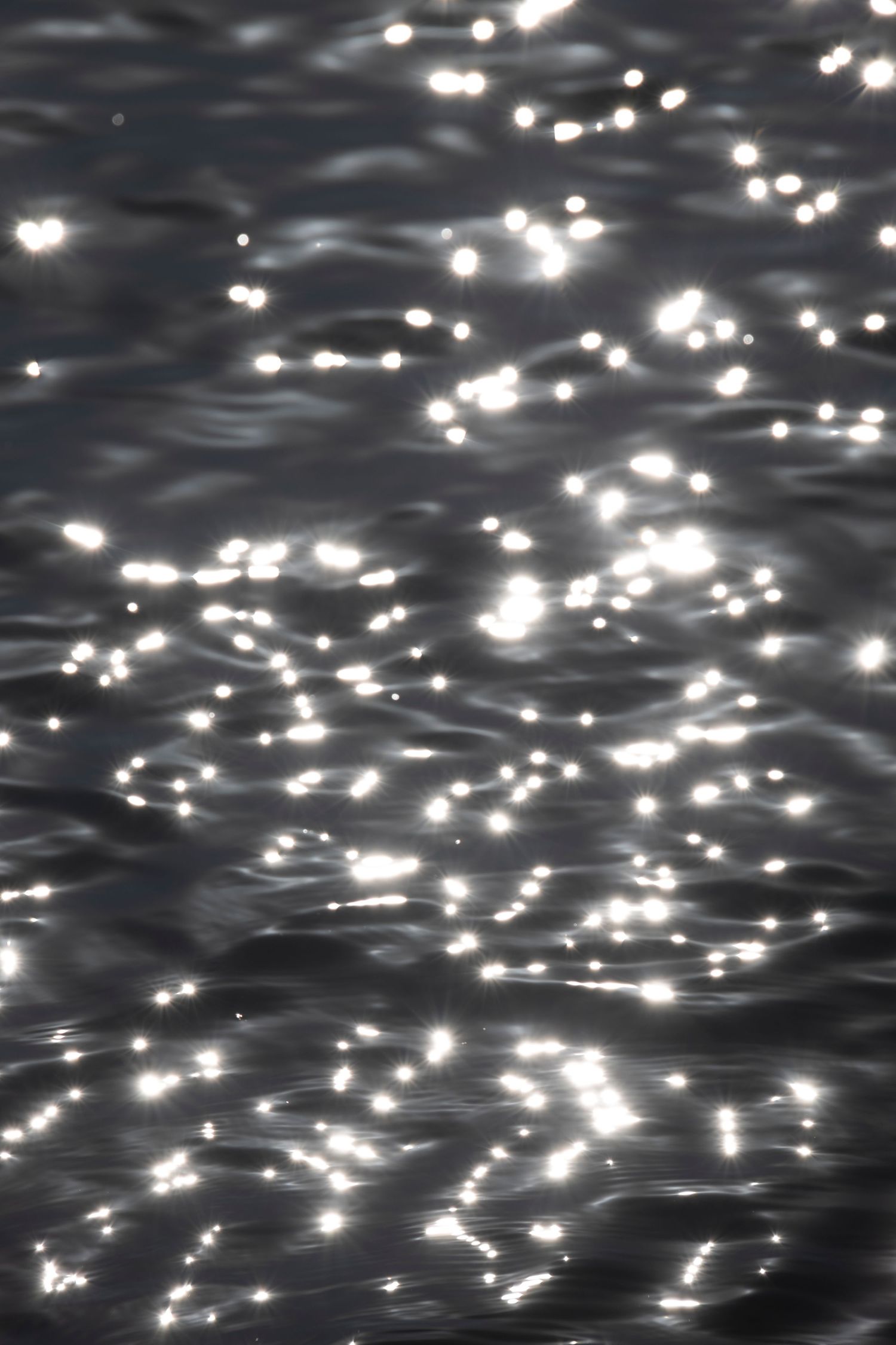 Sunlight reflecting as shimmering highlights across rippling dark water, creating a pattern of light and shadow.