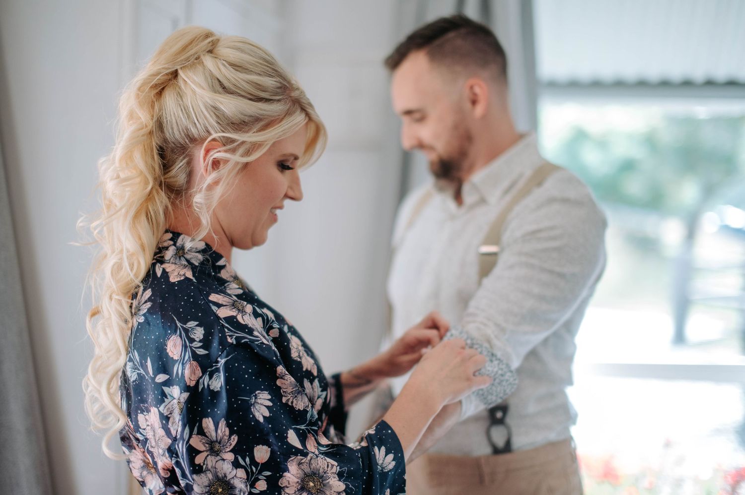 Wedding preparation moment with couple in formal attire helping each other get dressed.