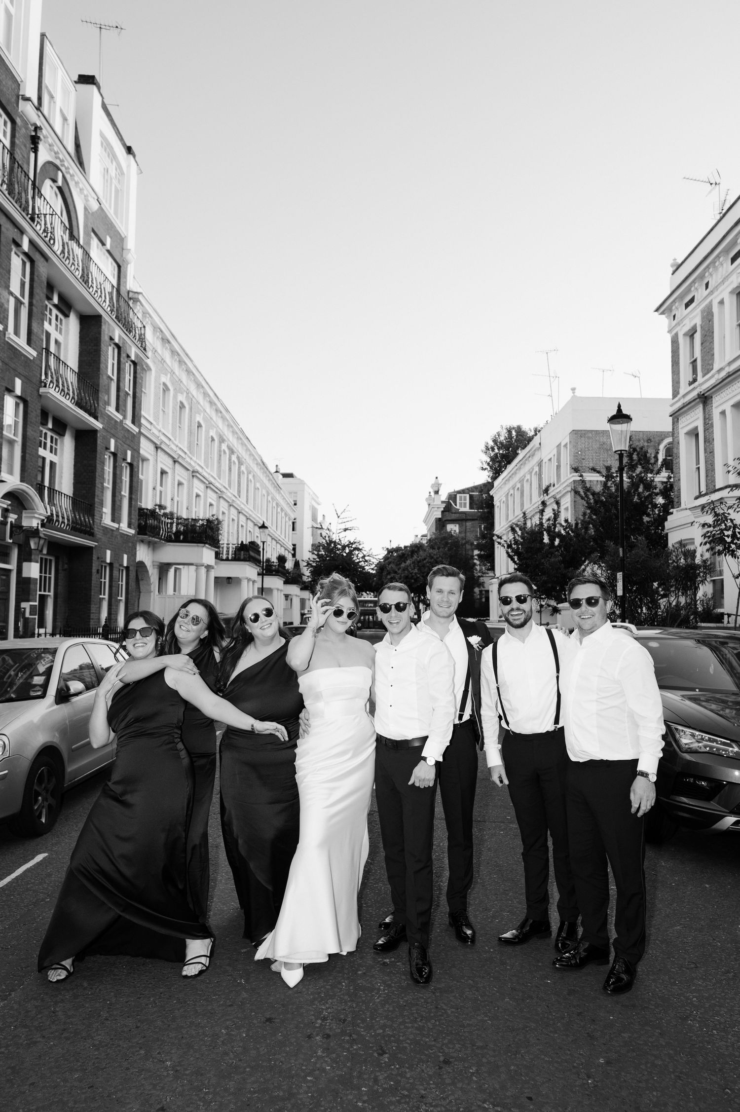 bridal party and groomsmen pose in the streets of London, taken by editorial wedding photographer based in Hampshire