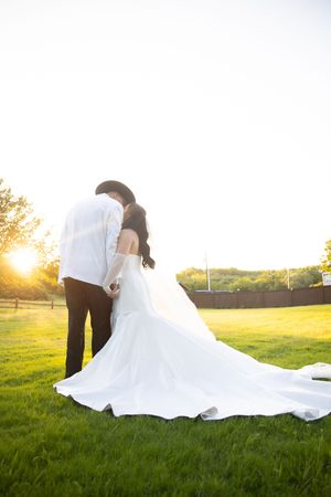 A romantic sunset wedding photo series showing a couple posing together on a grassy field.