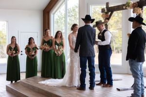 A wedding ceremony in a modern chapel with bridesmaids in green dresses and groomsmen in cowboy hats.