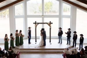 Overhead view of a wedding ceremony in a bright chapel with wooden beams and large windows.