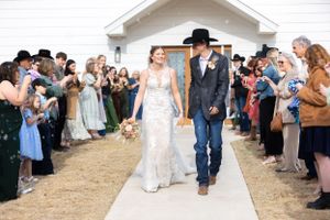 Wedding guests form an aisle outside a white chapel as the newlyweds make their exit.