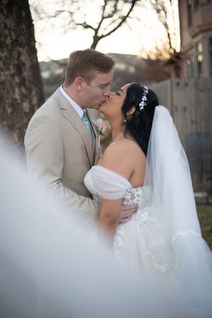 Romantic wedding couple embraces during outdoor portrait session at sunset.