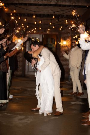 Wedding guests hold sparklers creating a tunnel for a romantic send-off moment.