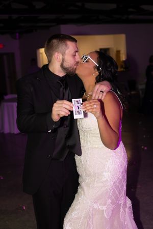 Couple shares intimate moment while holding playing cards at wedding reception.