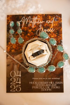 Wedding invitation with turquoise jewelry and black and white film displayed on rustic brown background.