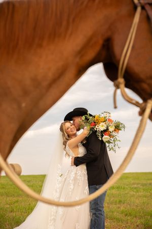 A couple shares a romantic dip-style dance pose in a grassy field with a dreamy, blurred background.