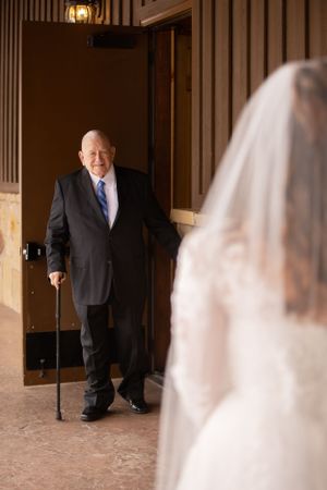 Emotional first look between father and bride in church hallway.