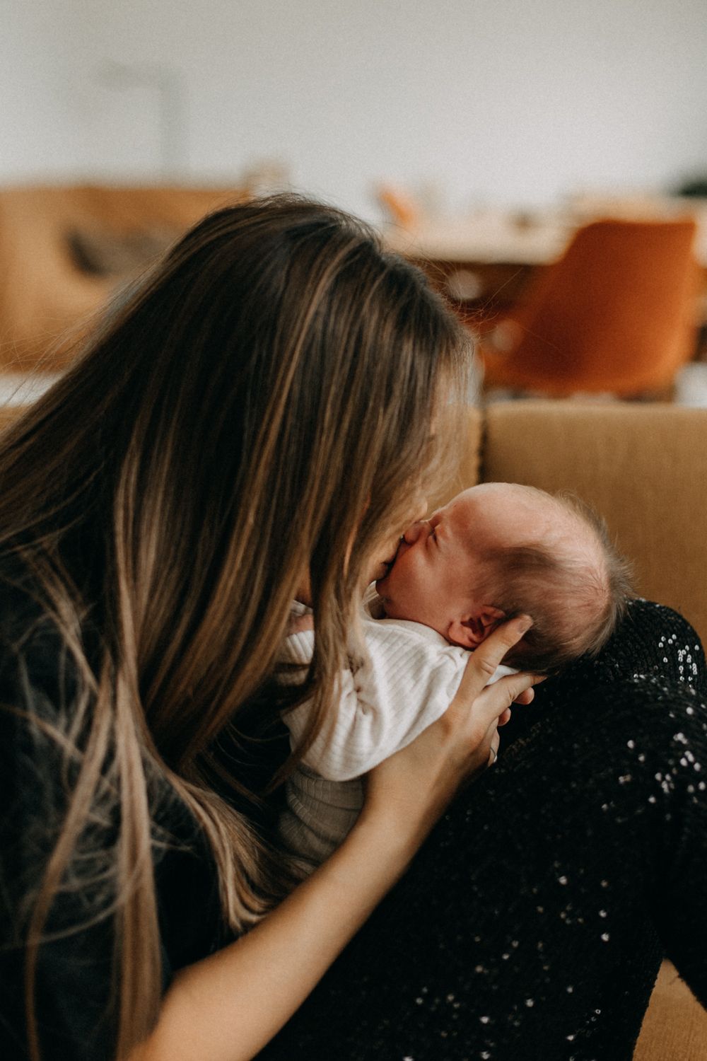 A tender bonding moment captured on a couch with warm lighting and sparkly black fabric.