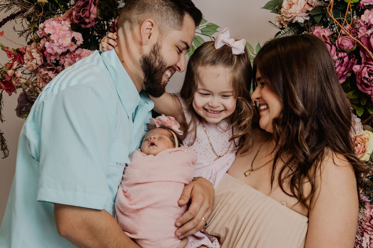 Happy family sharing tender moment under pink floral arch.