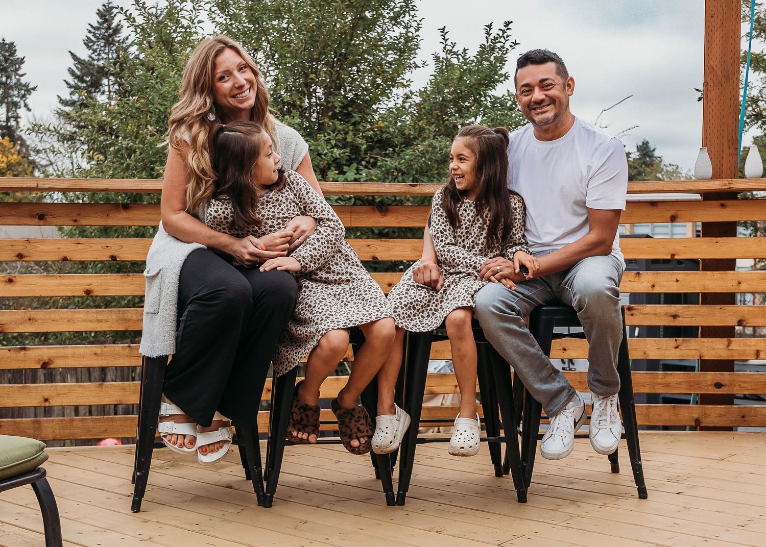 Beautiful family enjoying a casual outdoor moment together on wooden chairs on a patio.