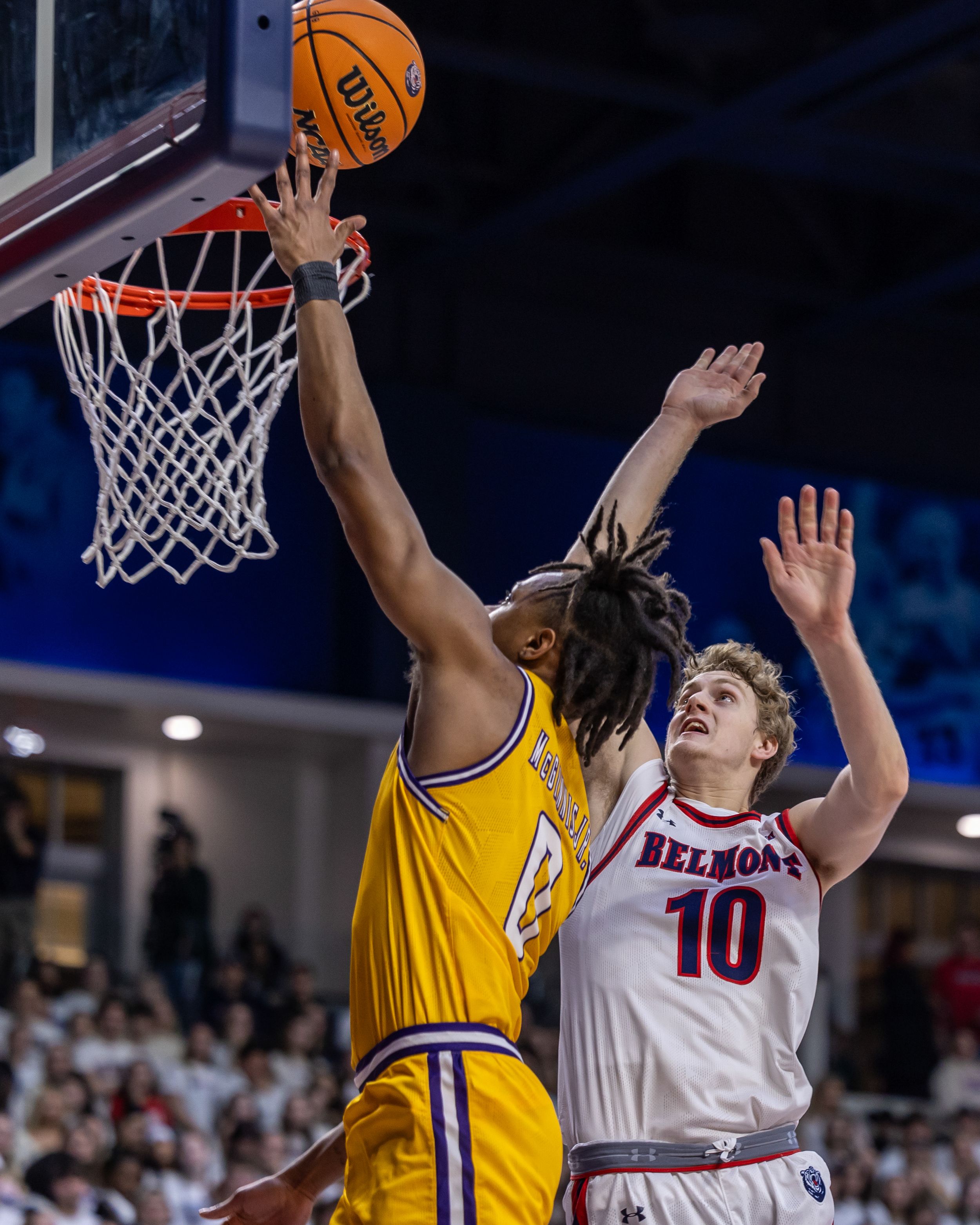 Basketball player in yellow jersey attempts a layup while Belmont defender number 10 contests the shot.