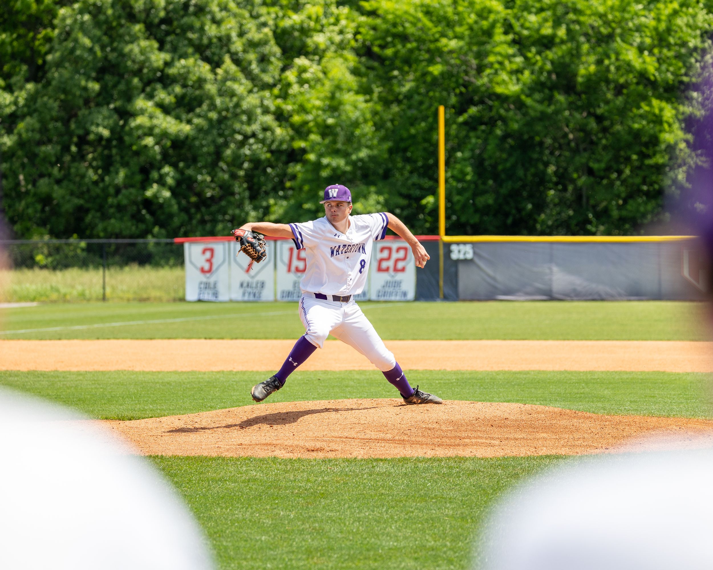 Baseball pitcher winds up for delivery on pitcher's mound during sunny game.