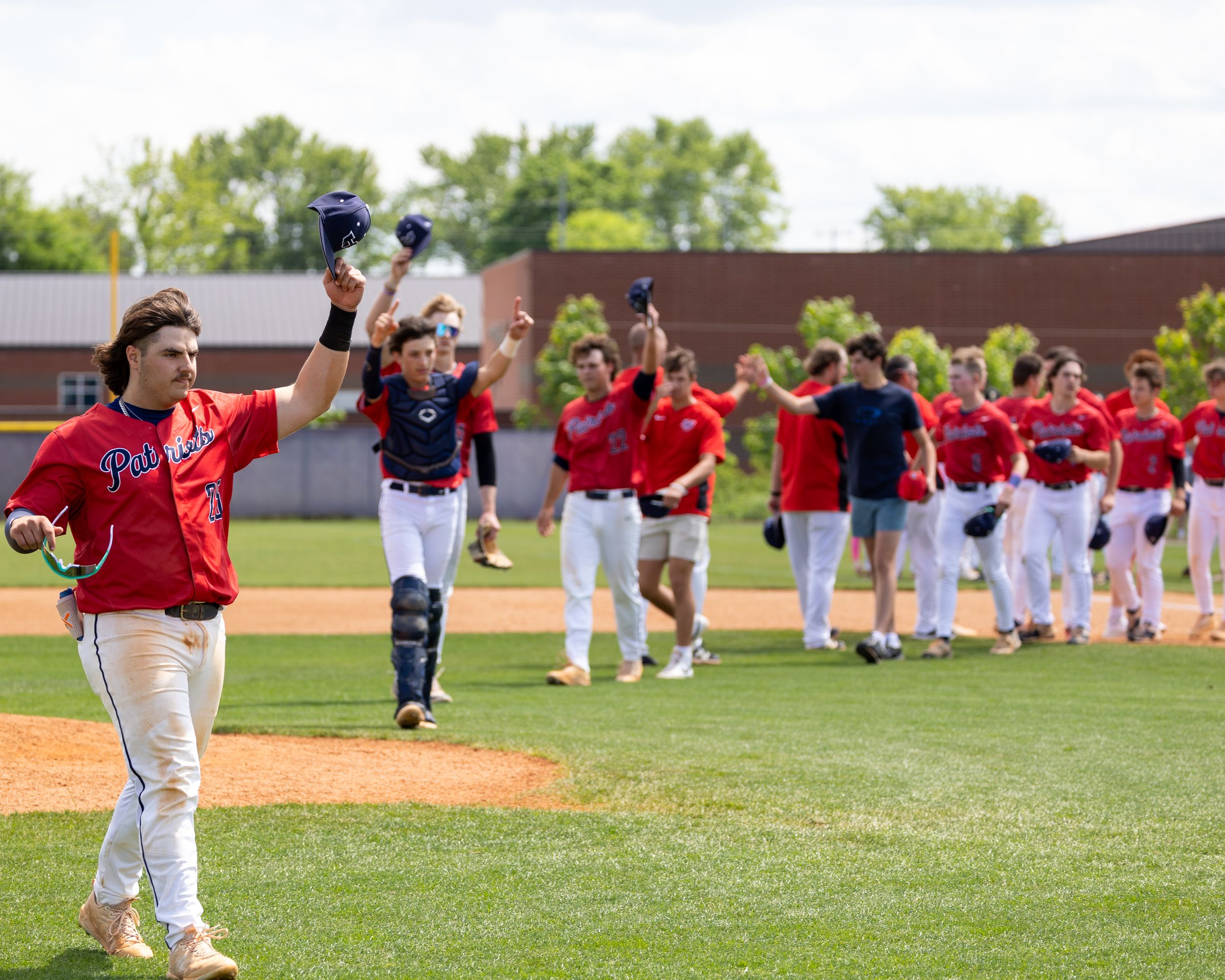 Red-uniformed baseball team celebrates victory walking across field together.