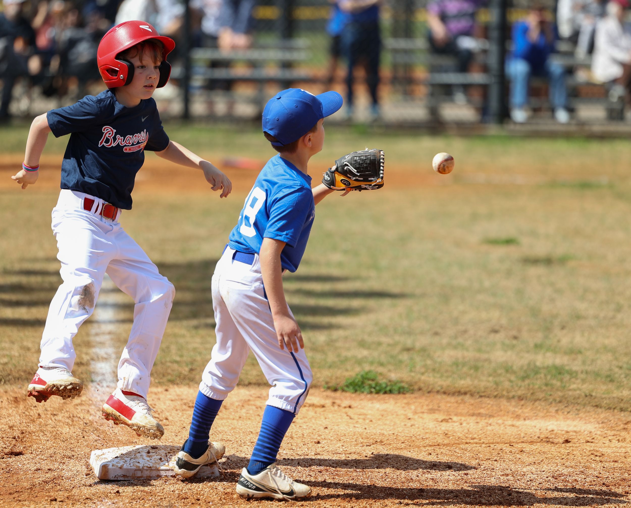 Young baseball players in action as a fielder catches the ball near first base during a youth game.