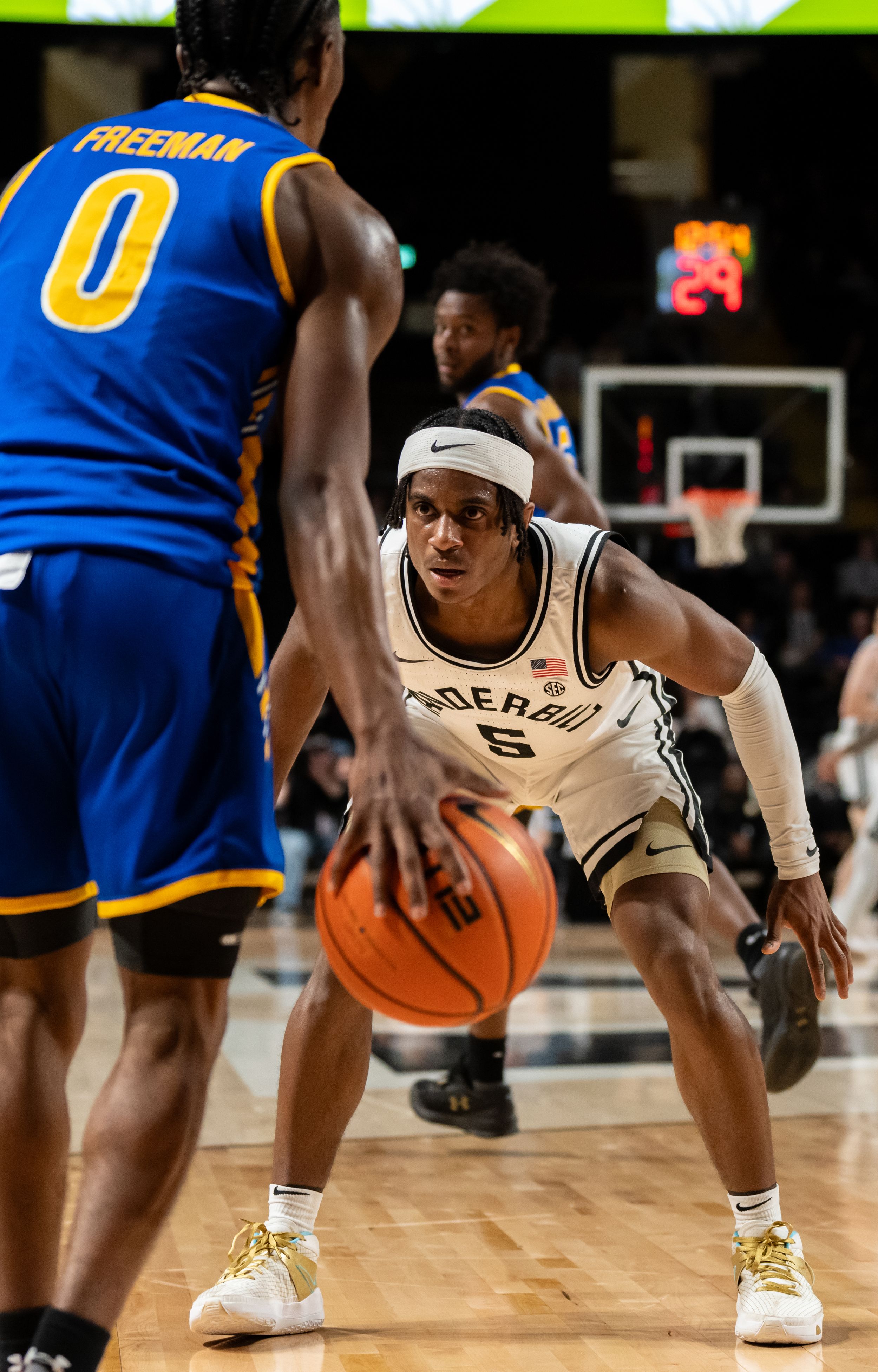 Vanderbilt basketball player in white uniform dribbles defensively against opponent number 0 Freeman in blue.