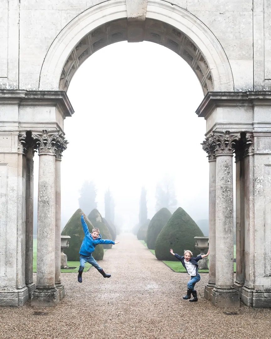 Family walking through a grand stone archway on a foggy day.