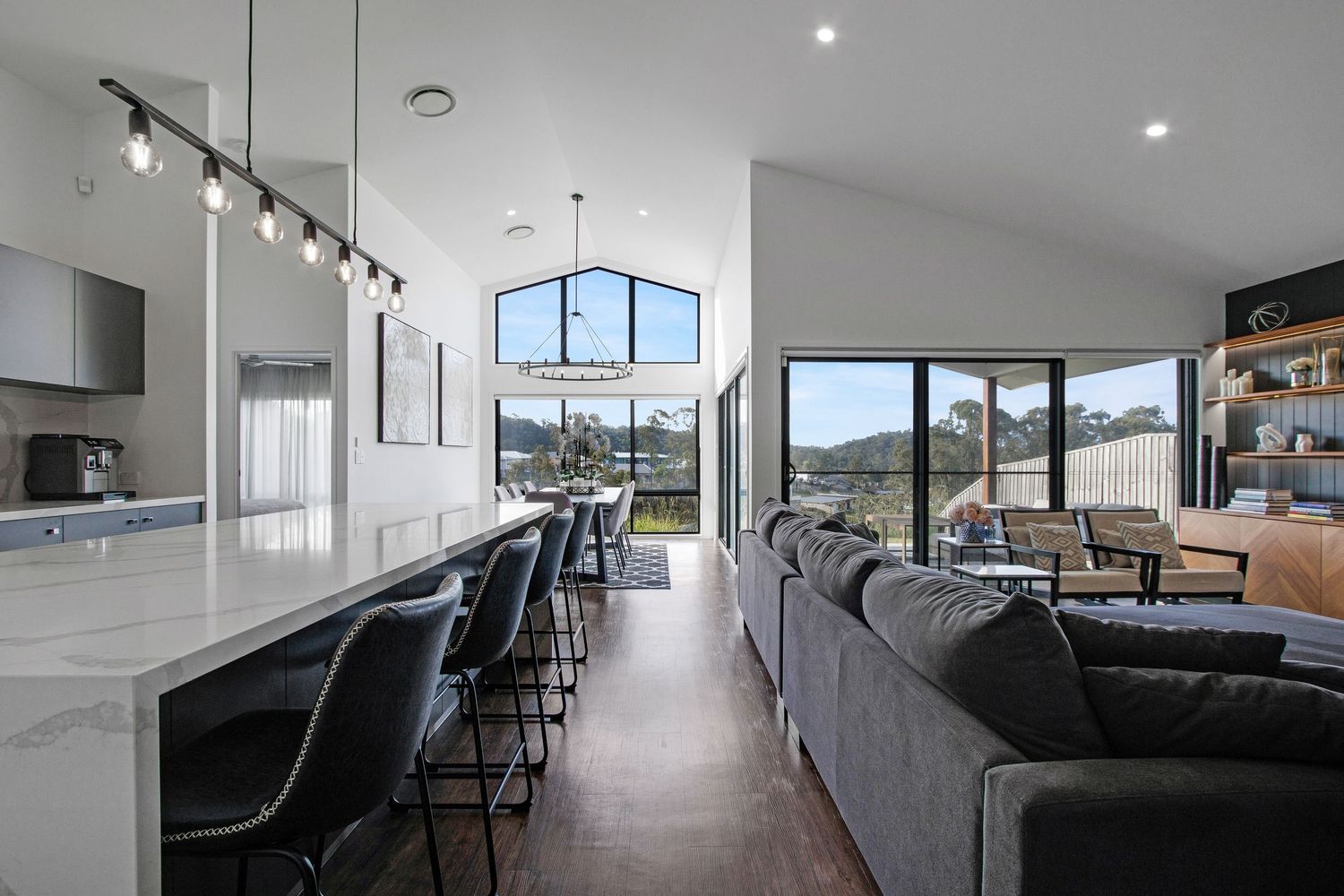 Spacious open-plan kitchen and living area with high ceilings and large windows, professionally photographed for real estate marketing.