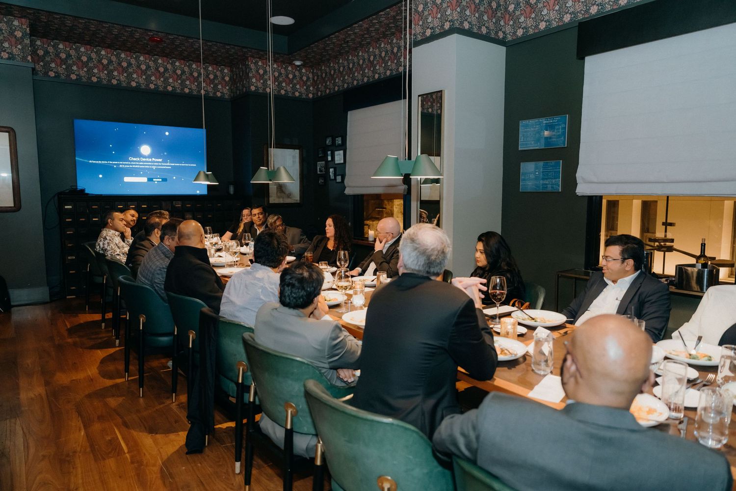 Business professionals seated at a formal dinner table during a corporate event with wine glasses and place settings.