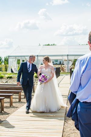 Wedding ceremony on wooden deck with white and purple decorations.