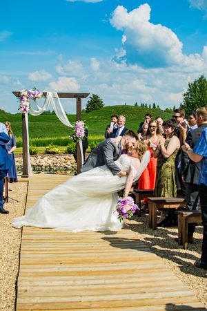 Wedding guests celebrating on an outdoor wooden deck platform under bright blue skies.