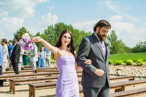 Wedding party members walking along a wooden deck pathway surrounded by green rolling hills.