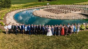 Panoramic view of an outdoor wedding ceremony setup with chairs on a grassy hillside overlooking scenic landscape.