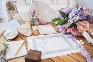 Wedding reception table settings with purple and pink floral arrangements, paper fans, and starfish decorations.