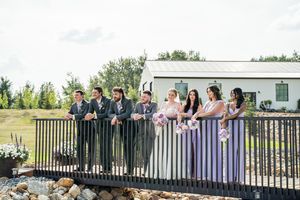 Wedding party posing together on a deck railing with scenic countryside views in the background.
