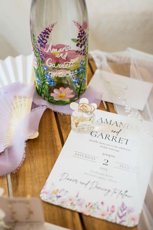 Elegant wedding place cards with watercolor floral designs and calligraphy displayed on a wooden table.