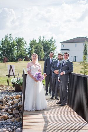 Wedding party poses on a wooden deck with stone landscaping and trees in the background.