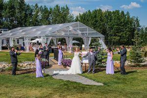 Panoramic view of an outdoor wedding ceremony setup with white tent and natural landscape.