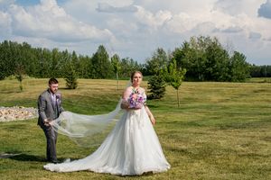 Wedding couple walks together across a scenic outdoor venue with rolling hills and greenery.