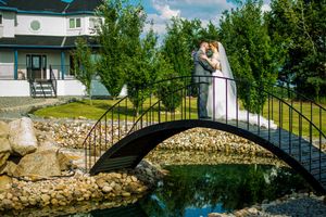 Wedding photography session on a decorative bridge over a peaceful pond surrounded by landscaped grounds.