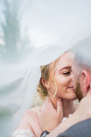 Romantic close-up moment between newlyweds under a delicate white veil.