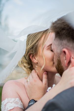 Close-up romantic moment captured through delicate white wedding veil.